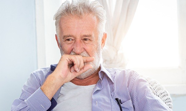 sneior man covering mouth in need of dentures