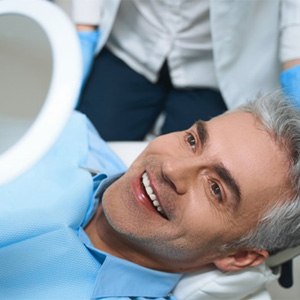 a patient checking his smile with a mirror 
