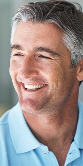 Man in blue shirt smiling after restorative dentistry
