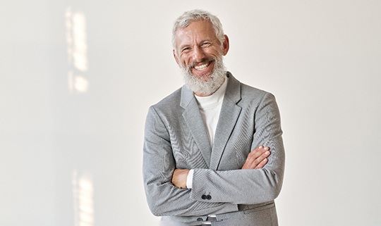 Man in grey business suit smiling with arms folded