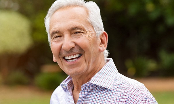Senior man in patterned shirt smiling outside