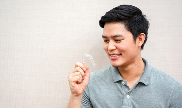 Young man smiling and looking at his ClearCorrect aligner
