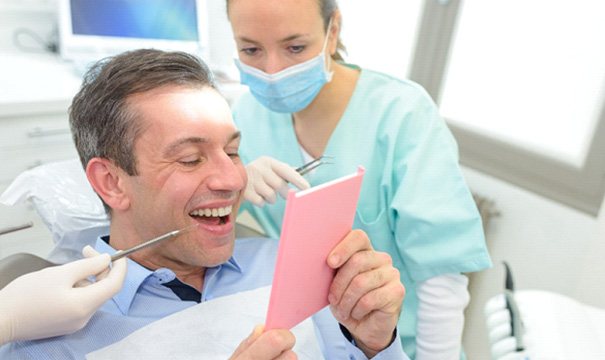 man smiling in dental mirror