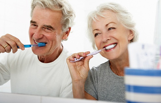 couple brushing teeth together in bathroom