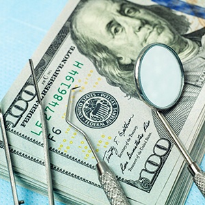 Dental tools sitting next to a stack of dollar bills