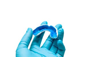 Dentist holding blue and white mouthguard with blue glove