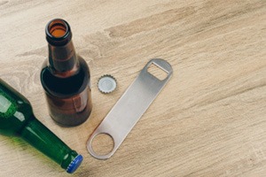 Bottle cap opener next to a brown and green bottle