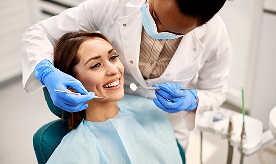 Dentist leaning over patient to examine her teeth