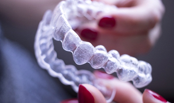 Close up of hand holding Invisalign in Attleboro aligner