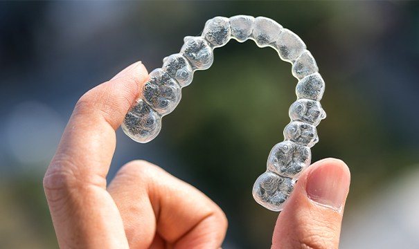 Invisalign tray held between fingers