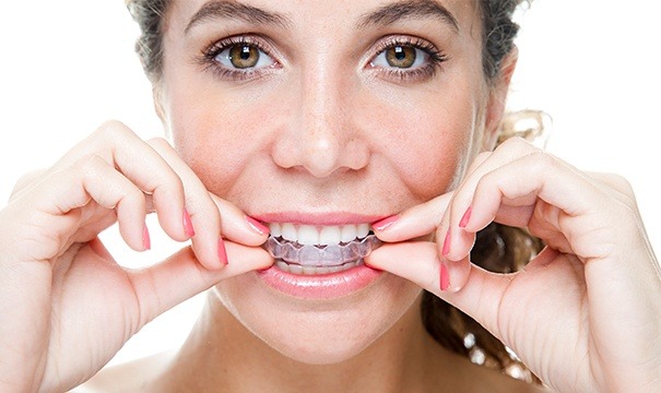 Woman inserting her invisalign tray over upper teeth
