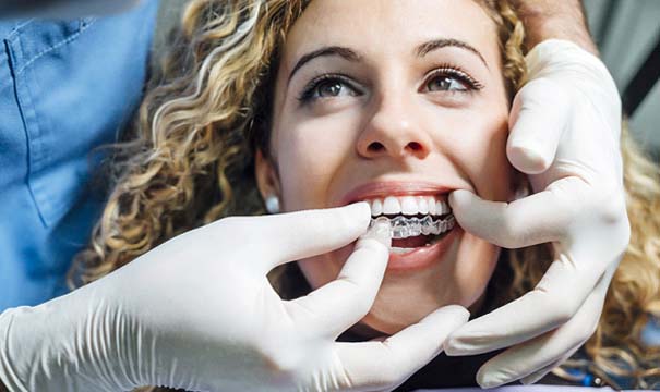 Dentist in Attleboro placing Invisalign aligner on patient
