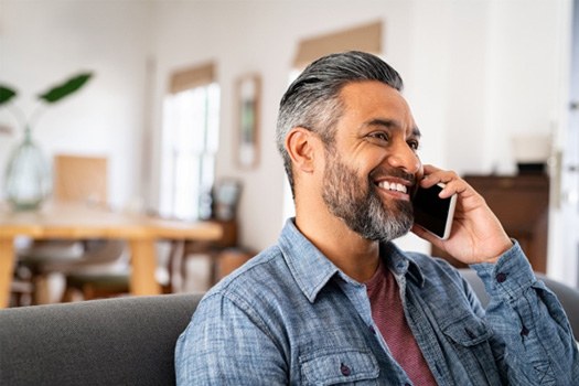 Man smiling while talking on phone at home