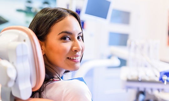 Female dental patient sitting in chair and smiling