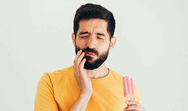 Man with tooth sensitivity holding cheek in pain