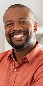 Man in orange smiling bright after cosmetic dentistry