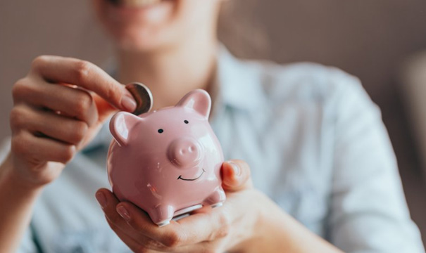 Woman dropping a coin into her piggy bank