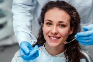 young woman smiling at her checkup with her dentist 