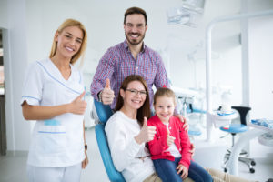 Family and dentist giving thumbs up