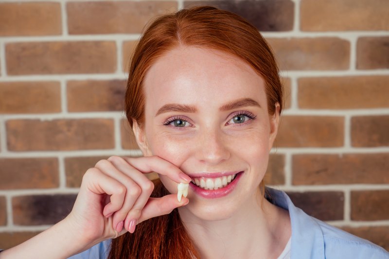 a young female holding an extracted tooth in Attleboro