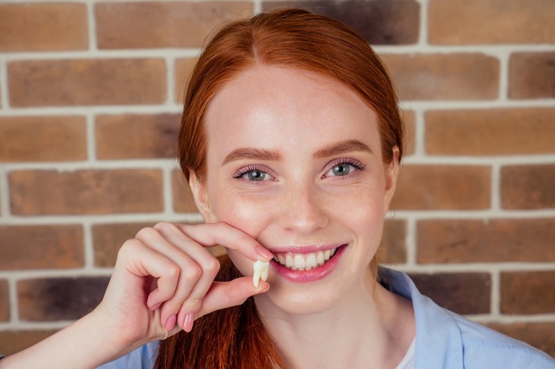 a young female holding an extracted tooth in Attleboro 