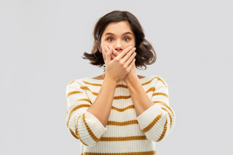 young woman with hand over mouth