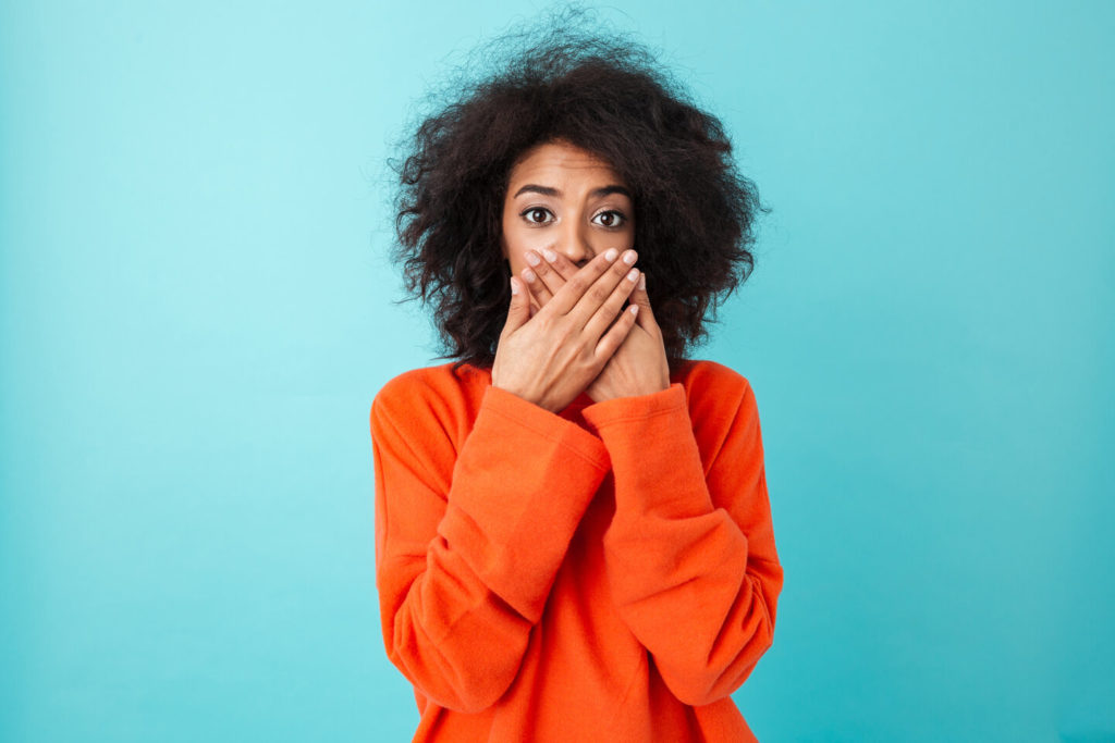 person with lost dental crown covering mouth with hands