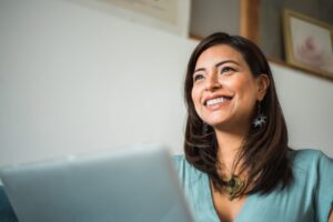 a smiling woman sitting in front of her laptop