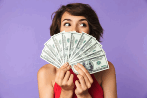 Woman hiding her smile behind a fan of bills